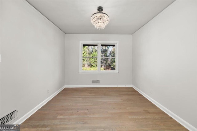 spare room featuring light hardwood / wood-style floors and a notable chandelier