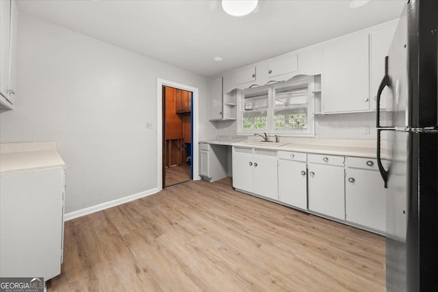 kitchen with white cabinets, refrigerator, sink, and light hardwood / wood-style flooring