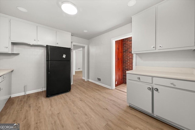 kitchen featuring black fridge, white cabinets, and light wood-type flooring