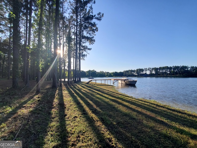 view of dock with a water view and a lawn