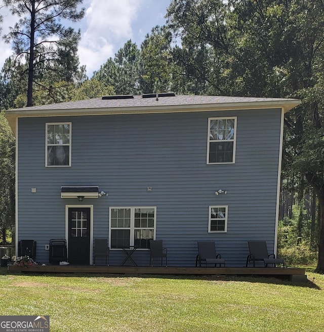 back of house featuring central AC unit and a lawn