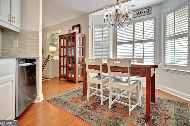 dining area with light wood-type flooring and an inviting chandelier