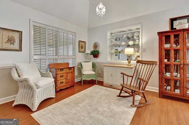 dining room featuring hardwood / wood-style floors, an inviting chandelier, a textured ceiling, and vaulted ceiling