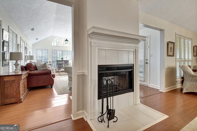 dining area featuring a tiled fireplace, wood-type flooring, and vaulted ceiling