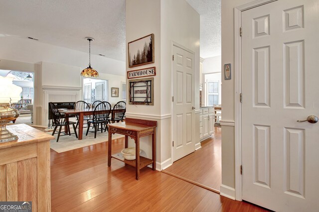 hall featuring a textured ceiling and light hardwood / wood-style flooring