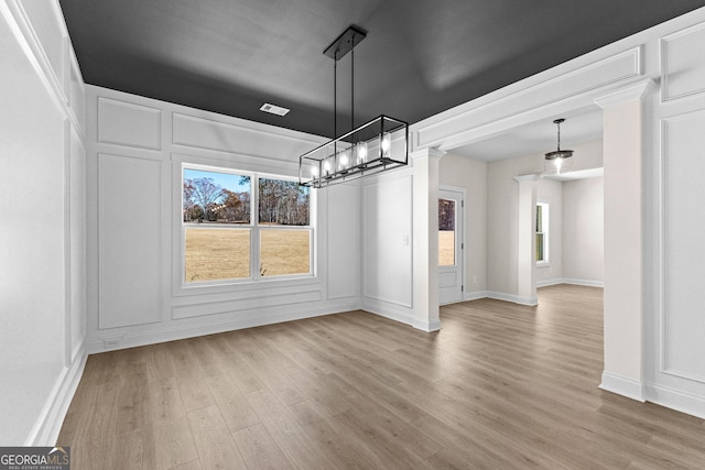 unfurnished dining area featuring a chandelier, a healthy amount of sunlight, and hardwood / wood-style flooring