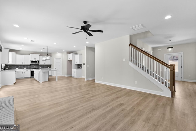 unfurnished living room with ceiling fan, light wood-type flooring, and sink