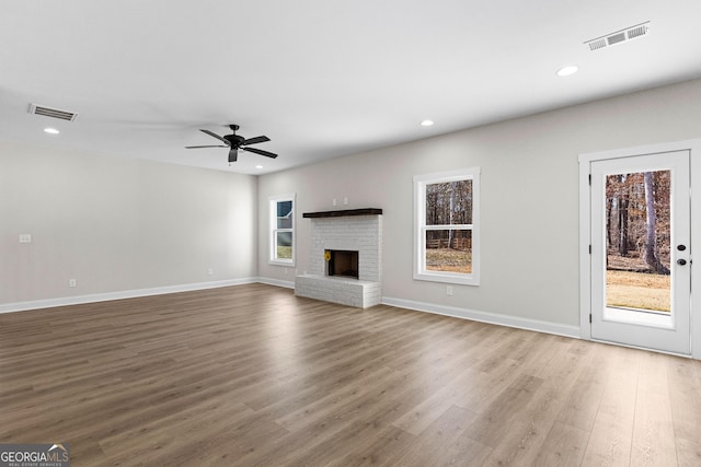 unfurnished living room featuring a wealth of natural light, ceiling fan, and a brick fireplace