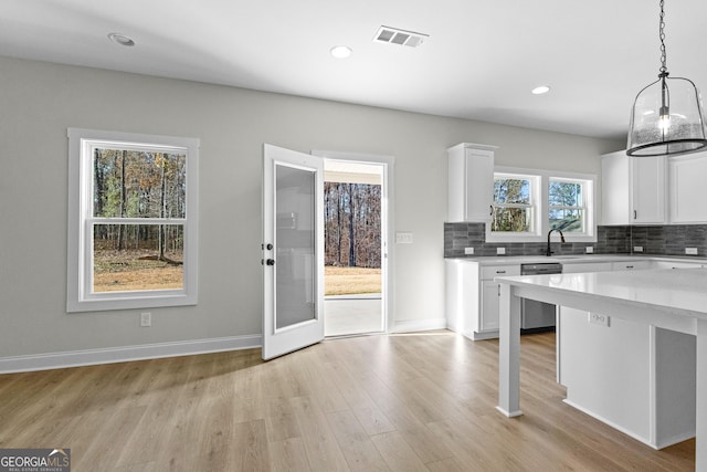 kitchen with dishwasher, pendant lighting, decorative backsplash, and white cabinetry