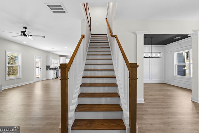 stairway with hardwood / wood-style flooring, ceiling fan with notable chandelier, and sink