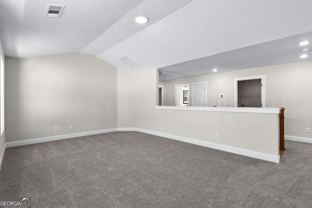 unfurnished room with dark colored carpet and lofted ceiling