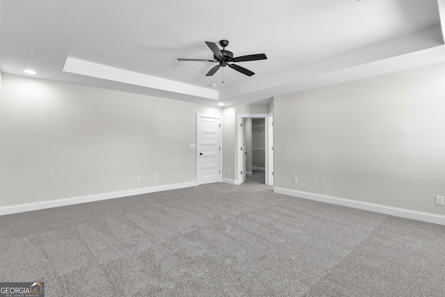 unfurnished room featuring carpet floors, a tray ceiling, and ceiling fan