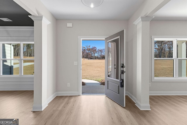 foyer with light hardwood / wood-style floors, ornate columns, and a wealth of natural light