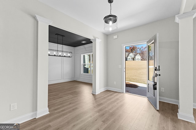 entryway with decorative columns, a healthy amount of sunlight, and light wood-type flooring