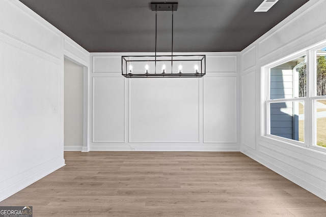 unfurnished dining area featuring light hardwood / wood-style floors and a chandelier