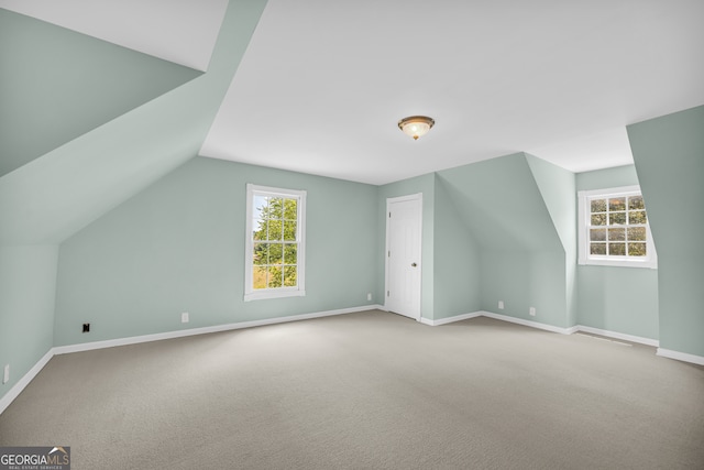 additional living space featuring light colored carpet and vaulted ceiling