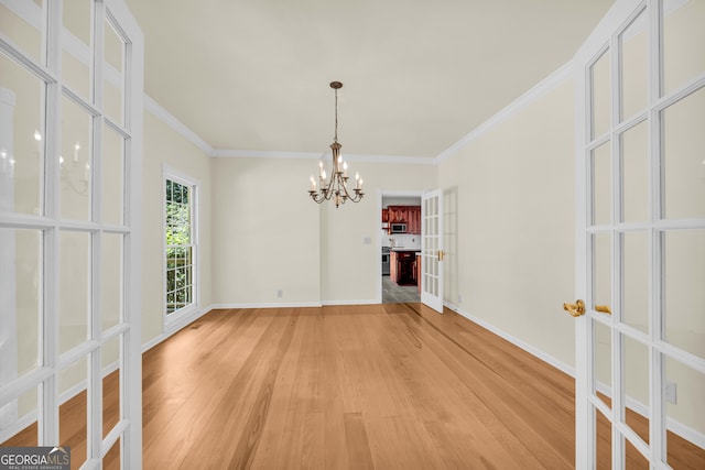 unfurnished dining area featuring a chandelier, hardwood / wood-style flooring, and ornamental molding