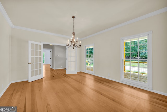 unfurnished dining area with crown molding, french doors, plenty of natural light, and an inviting chandelier