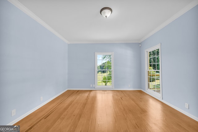 spare room featuring ornamental molding, a wealth of natural light, and light hardwood / wood-style flooring