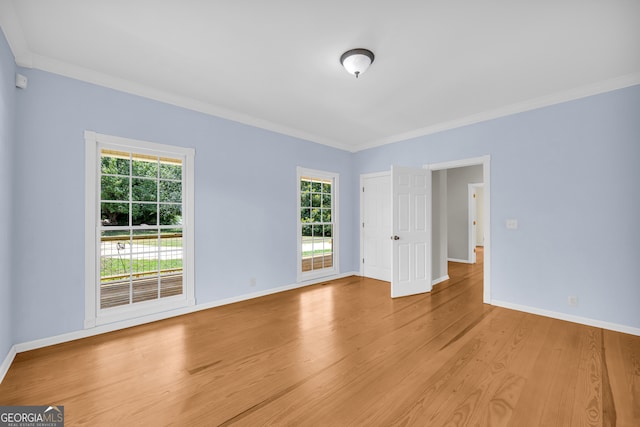 spare room with light hardwood / wood-style floors, a healthy amount of sunlight, and ornamental molding