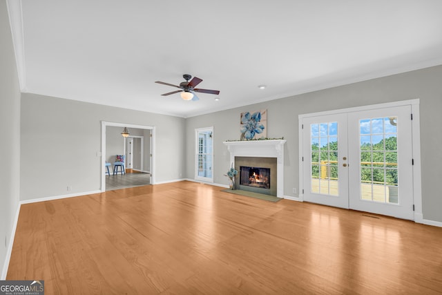 unfurnished living room featuring french doors, light hardwood / wood-style flooring, ceiling fan, and crown molding