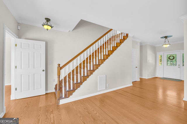 foyer with wood-type flooring and ornamental molding