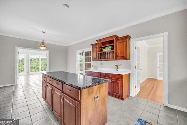 kitchen featuring a center island, dark stone counters, crown molding, and light tile patterned flooring