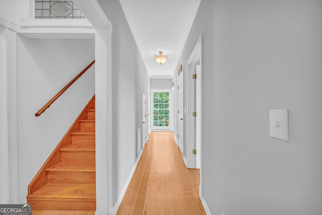 corridor with light hardwood / wood-style floors and crown molding