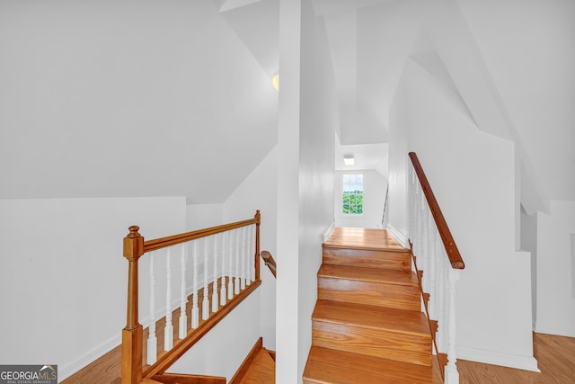 stairway featuring hardwood / wood-style floors and vaulted ceiling