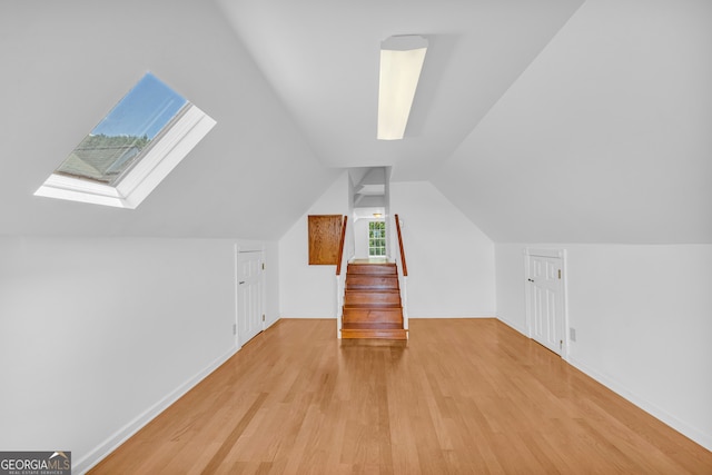 additional living space with light hardwood / wood-style flooring and lofted ceiling with skylight