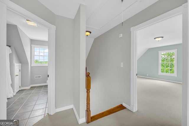 hall with lofted ceiling, light colored carpet, and a healthy amount of sunlight