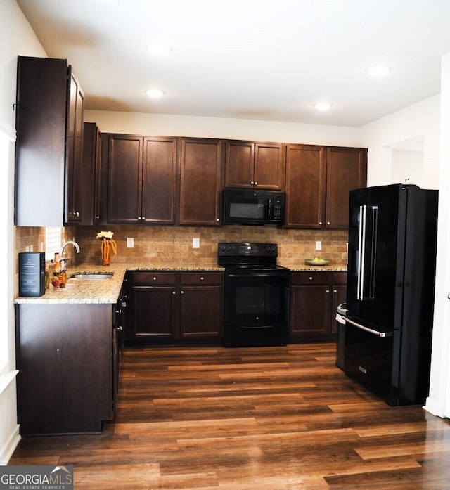 kitchen featuring dark brown cabinets, black appliances, dark wood-type flooring, and a sink