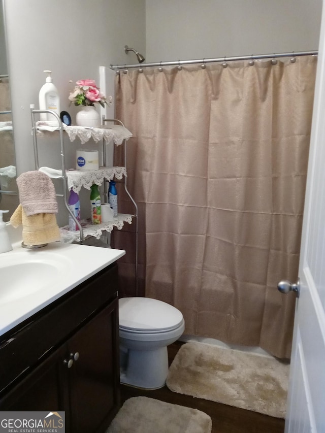 bathroom with a shower with shower curtain, vanity, and toilet