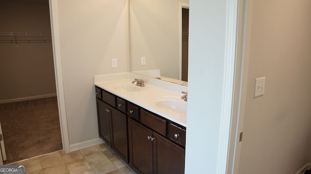 full bathroom with a walk in closet, double vanity, and a sink