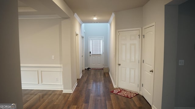 corridor featuring visible vents, wood finished floors, wainscoting, and a decorative wall