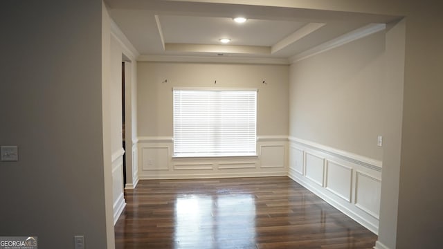 unfurnished room with dark wood finished floors, a decorative wall, and a tray ceiling