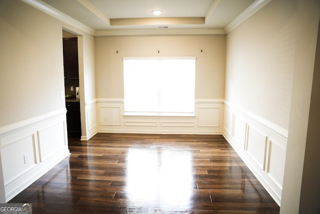 unfurnished room with a raised ceiling, a decorative wall, and dark wood-style flooring