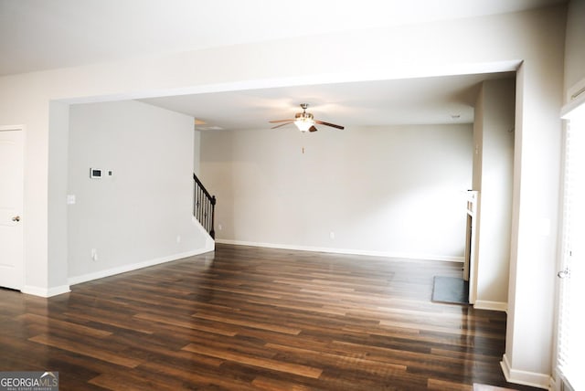 spare room with dark wood finished floors, stairway, a ceiling fan, and baseboards