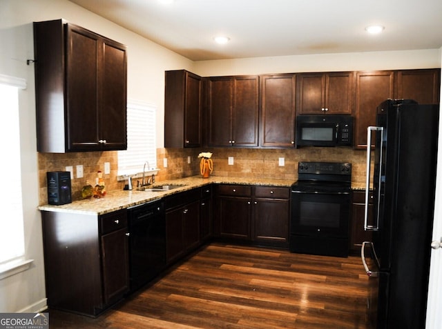 kitchen with dark brown cabinets, dark wood-type flooring, light stone countertops, black appliances, and a sink