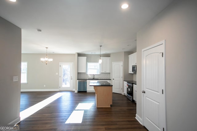 kitchen featuring a center island, white cabinets, stainless steel appliances, and decorative light fixtures