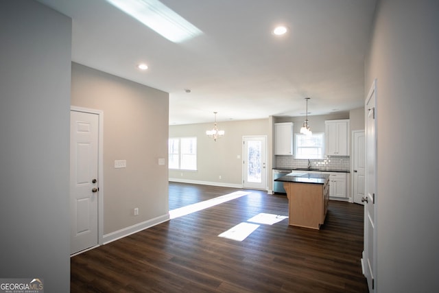 kitchen with dishwasher, white cabinetry, hanging light fixtures, a center island, and tasteful backsplash