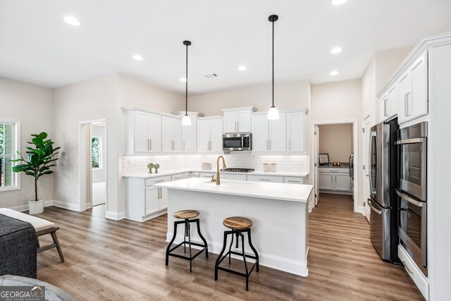 kitchen featuring white cabinets, appliances with stainless steel finishes, and hanging light fixtures