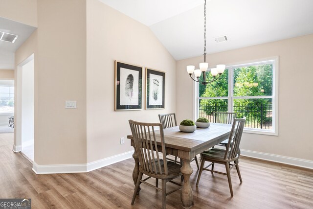 dining area featuring vaulted ceiling, light hardwood / wood-style flooring, and a chandelier