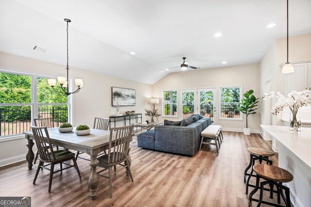 dining area featuring ceiling fan with notable chandelier, a healthy amount of sunlight, light hardwood / wood-style floors, and lofted ceiling