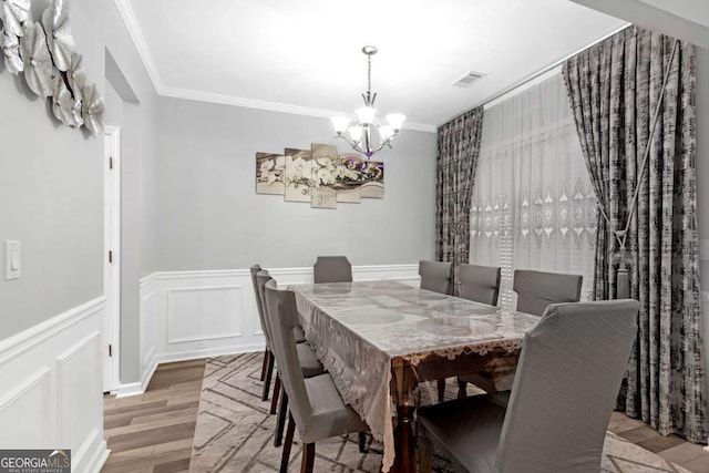 dining room with hardwood / wood-style floors, a notable chandelier, and crown molding