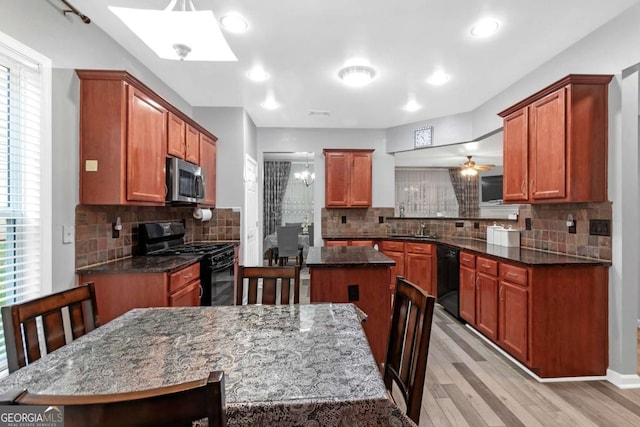 kitchen featuring dark stone counters, black appliances, sink, light hardwood / wood-style floors, and a kitchen island