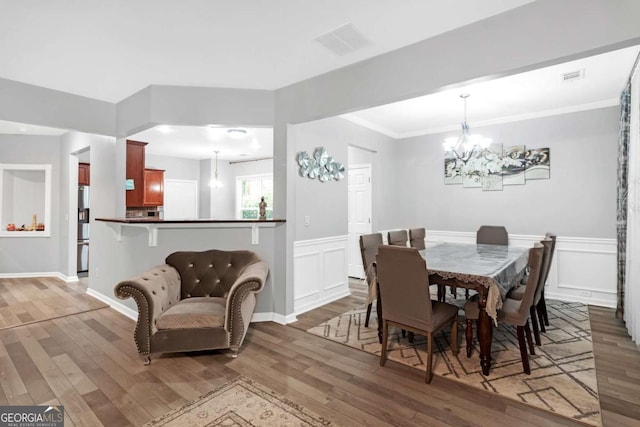 dining area featuring dark hardwood / wood-style flooring, ornamental molding, and an inviting chandelier