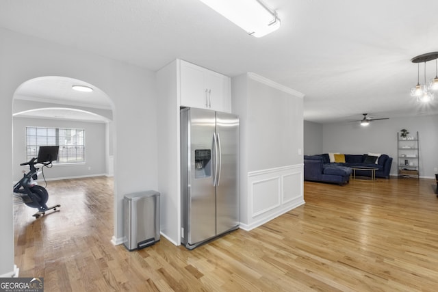 kitchen featuring white cabinets, crown molding, ceiling fan, light wood-type flooring, and stainless steel fridge with ice dispenser