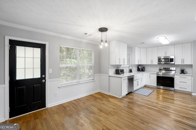 kitchen featuring backsplash, light wood-type flooring, stainless steel appliances, decorative light fixtures, and white cabinets