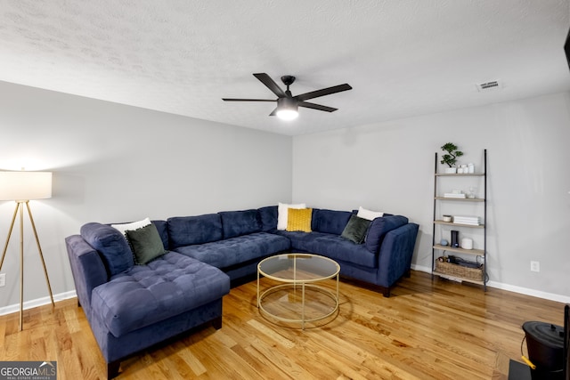 living room with ceiling fan, wood-type flooring, and a textured ceiling